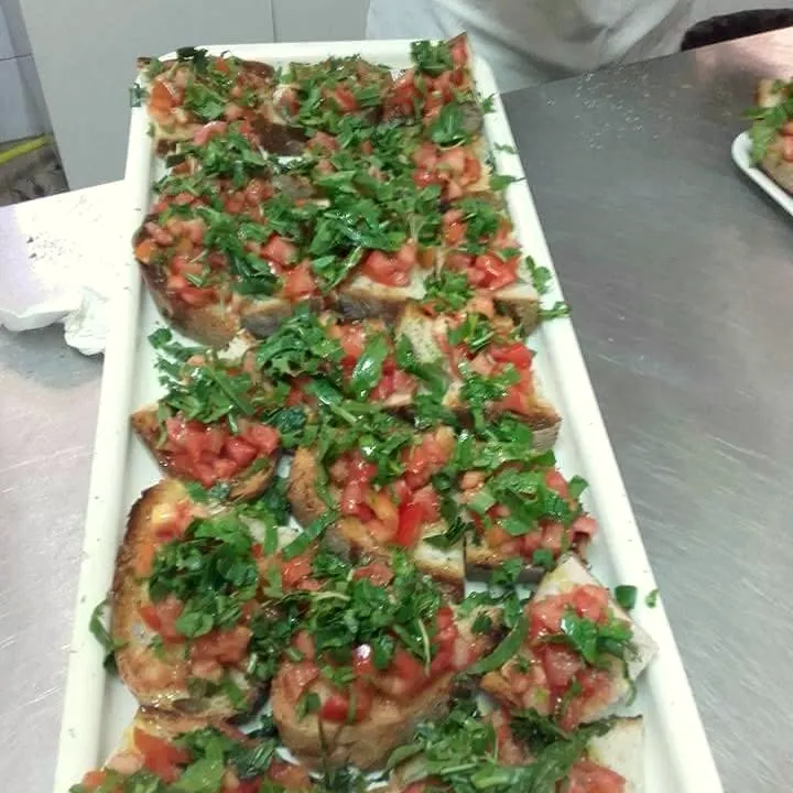 Lange Platte mit Bruschetta, belegt mit Tomaten und Rucola