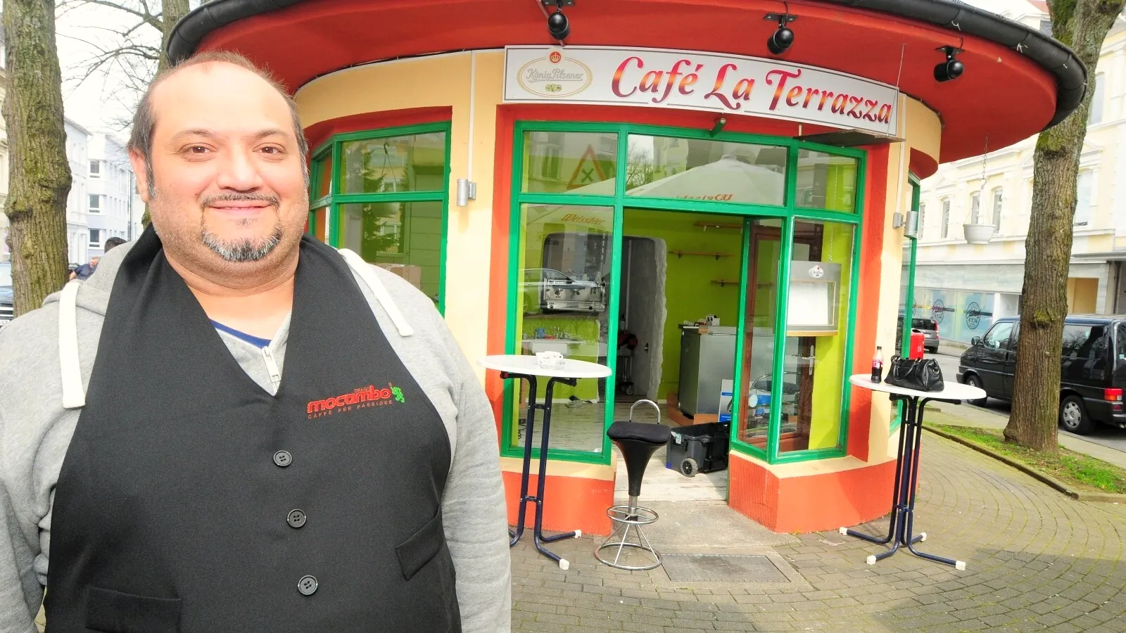 Manuel, der Inhaber, lächelt vor seinem runden Pavillon mit dem Schriftzug Café La Terrazza